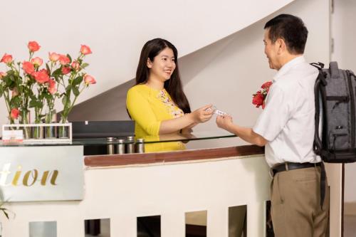 a man and a woman standing at a reception desk at Hue Harmony Hotel in Hue