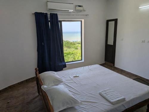 una cama en una habitación con una ventana grande en ANV Beach house, en Kovakulam