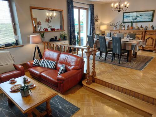 - un salon avec un canapé en cuir et une salle à manger dans l'établissement Holiday Home des Aulnes by Interhome, à Cléder
