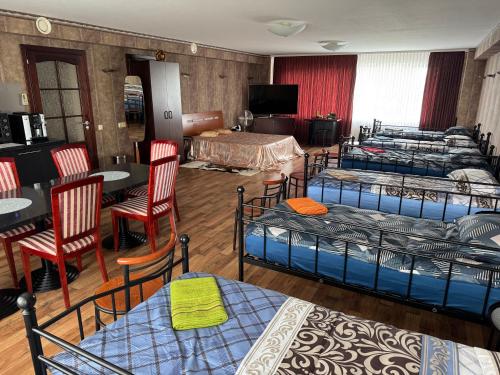 a room with four beds and a table and chairs at Baskervilu Muiža in Sērenes