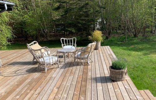 a wooden deck with a table and chairs on it at Familiesommerhus Med Stor Terrasse I Rørvig in Rørvig