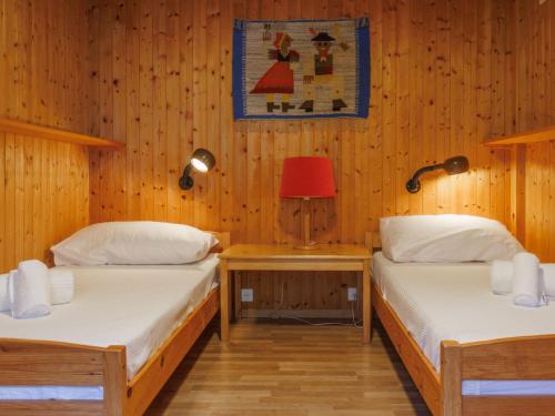 two beds in a room with wooden walls at Chalet Coquelicot by Interhome in Zinal