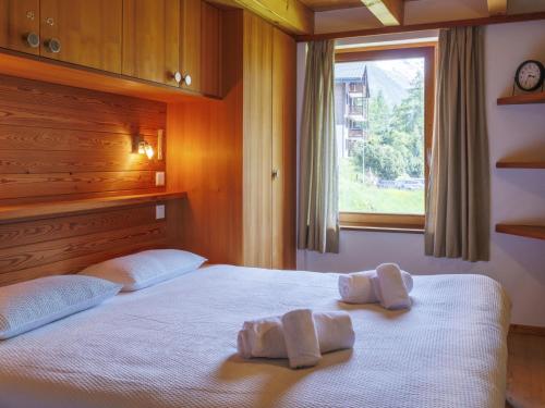 a bedroom with two towels on a bed with a window at Apartment Ryad C by Interhome in Zinal