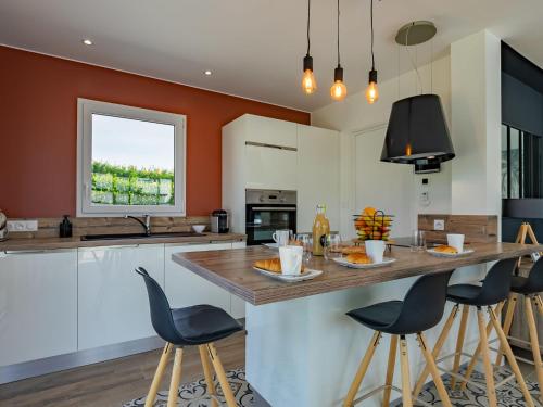 une cuisine avec des murs orange et un grand îlot avec des tabourets de bar dans l'établissement Holiday Home Villa Ty Coz by Interhome, à Cléder