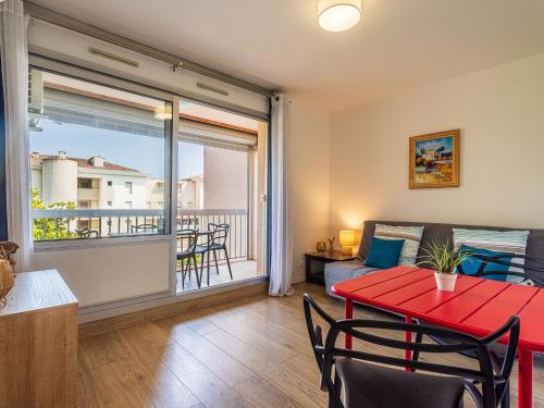 d'un salon avec une table rouge et un balcon. dans l'établissement Apartment Le Zodiaque II-3 by Interhome, à Hyères