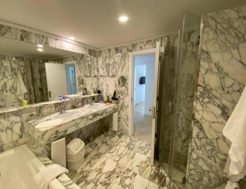 a bathroom with two sinks and a glass shower at Anfi Del Mar 1 in La Playa de Arguineguín
