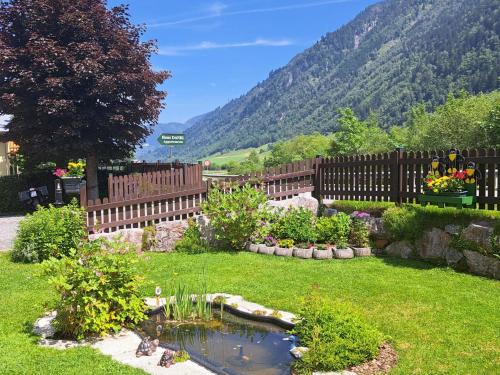 a garden with a fence and a pond in the grass at Apartment Apartement Haus Dankl by Interhome in Fusch an der Glocknerstraße