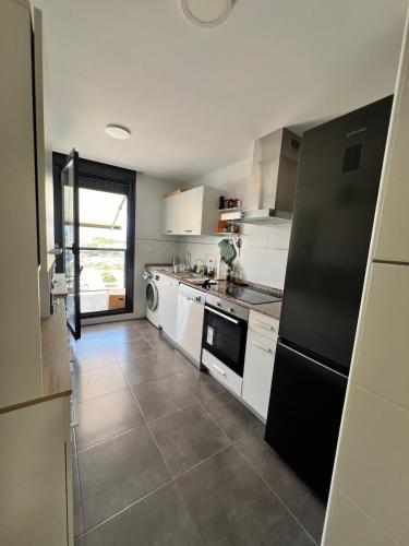 a kitchen with white cabinets and a black refrigerator at Apartment in campello Beach in El Campello