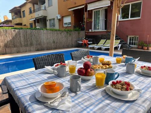 a table with a breakfast of fruit and juice next to a pool at Holiday Home La Victoria by Interhome in Palafrugell