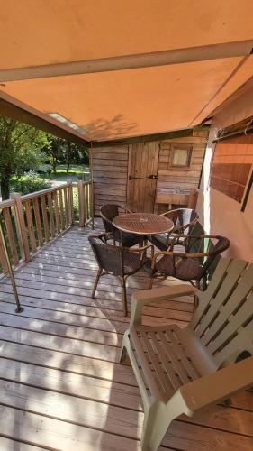 une terrasse en bois avec une table et des chaises dessus dans l'établissement Camping La Fritillaire, à Savigny-en-véron