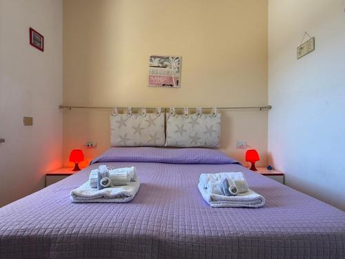 Casa Valentina في توري دي كورساري: غرفة نوم بسرير ارجواني عليه مناشف