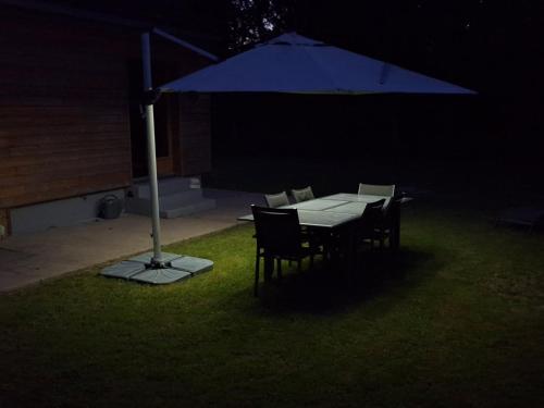 a table and chairs under an umbrella at night at Gîte des giblins - Saint Amand en Puisaye in Saint-Amand-en-Puisaye