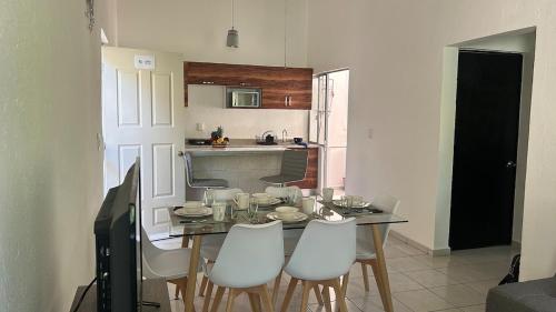 a kitchen with a dining table and white chairs at Terrazas Huatulco in Santa Cruz Huatulco