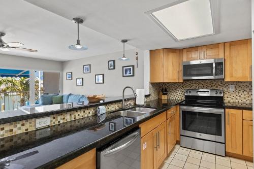 a kitchen with stainless steel appliances and wooden cabinets at Dolphin Cove- Pet Friendly Waterfront Townhome w Pool in Marathon