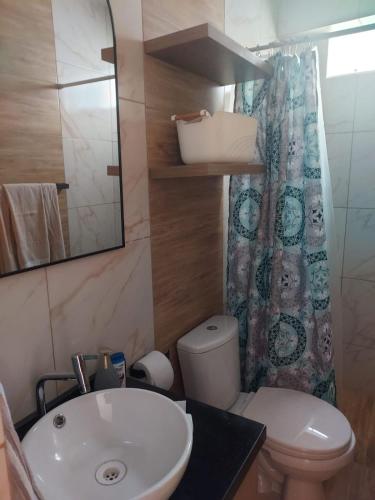 a bathroom with a sink and a toilet and a mirror at Amplio departamento en Ica in Ica