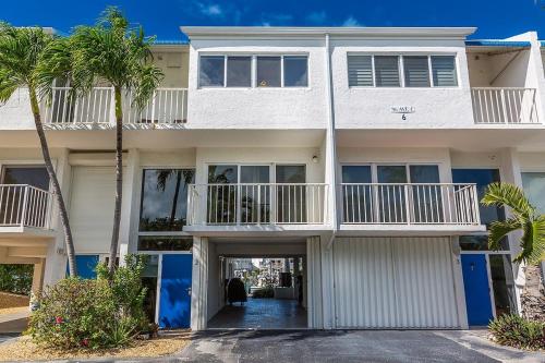 a white house with palm trees in front of it at Dolphin Cove- Pet Friendly Waterfront Townhome w Pool in Marathon