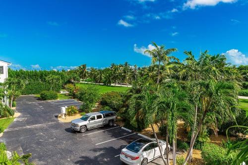 two cars parked in a parking lot with palm trees at Dolphin Cove- Pet Friendly Waterfront Townhome w Pool in Marathon
