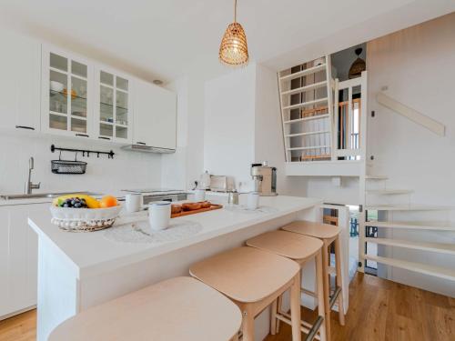 une cuisine avec des armoires blanches et un comptoir avec des tabourets dans l'établissement Apartment Coudalère-Les Hébrydes-2 by Interhome, au Barcarès