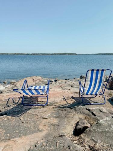 two blue and white chairs sitting on a rocky beach at Island House On Private Island With Sea View in Östhammar