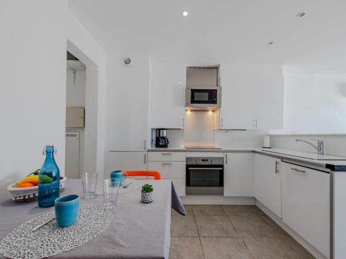une cuisine avec des placards blancs et une table avec des tasses bleues dans l'établissement Apartment Palmyra-9 by Interhome, au Barcarès