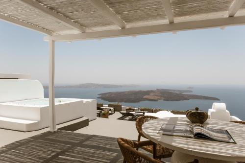 a patio with a table and a view of the ocean at Aqua Luxury Suites by NOMÉE Hospitality Group in Imerovigli