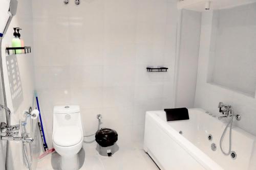 a white bathroom with a toilet and a bath tub at Bollywood House 100 inch Cinema Jacuzzi Party Couples in Gurgaon