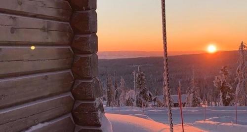 a swing with the sunset in the background at Cozy Log Cabin With A View Over Hedmarken in Løten