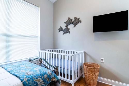 a nursery with a crib and a tv on the wall at You're On Island Time in this 4 BR in Quiet Neighb in Sampson