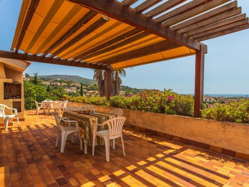 un patio avec une table et des chaises sous une pergola dans l'établissement Holiday Home Maison Heliosa by Interhome, à Bormes-les-Mimosas