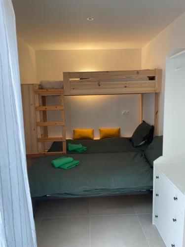 a small bedroom with a bunk bed with green sheets at mini villa neuve moderne proche des plages in Brétignolles-sur-Mer