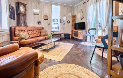 a living room with a leather couch and a tv at Cozy Home In Les Eyzies in Les Eyzies-de-Tayac