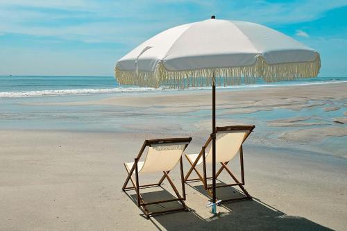 two chairs sitting under an umbrella on the beach at 3BR 3BA with Golf Course View from screened lanai 1226 in Sampson