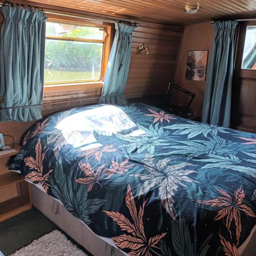 un lit dans un camping-car avec un couvre-lit fleuri dans l'établissement Bateau de charme cosy, à Pont-de-Vaux