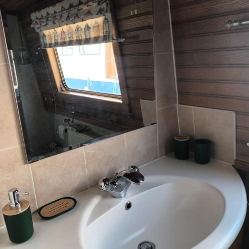 La salle de bains est pourvue d'un lavabo blanc et d'une fenêtre. dans l'établissement Bateau de charme cosy, à Pont-de-Vaux