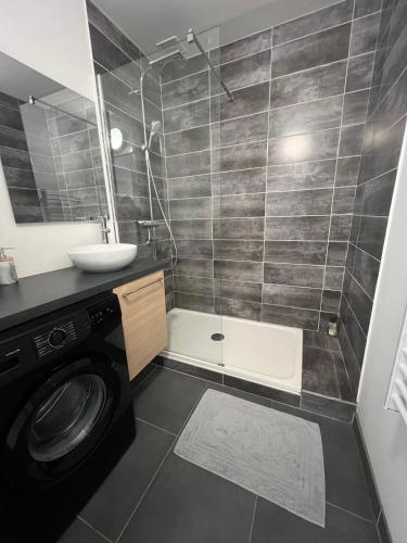 une salle de bain avec une machine à laver et un lavabo dans l'établissement La Parisienne - 80m2, à Vierzon
