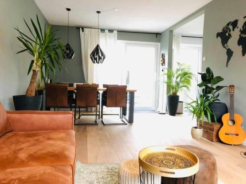 a living room with a couch and a table with a guitar at Gezellig, volledig ingericht huis in Nijmegen in Nijmegen