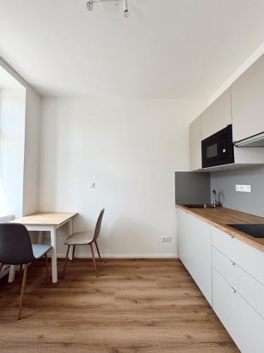 a kitchen with white cabinets and a table and chairs at SuperNova Apartments in Brno
