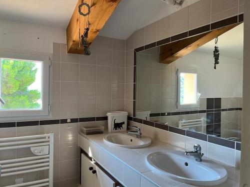 une salle de bain avec deux lavabos et un grand miroir dans l'établissement Maison village provençal, à Éguilles