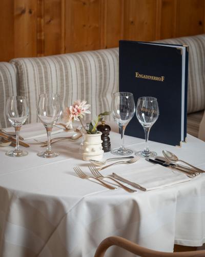 a table with wine glasses and a blue box on it at Boutique Hotel Engadinerhof - A Home for Generations in Pontresina