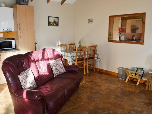a living room with a leather couch and a table at Ploughman's Cottage in Flamborough