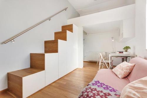 a living room with a staircase and a pink couch at modern studio apartment in the heart of old city in Ljubljana