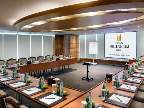a conference room with long tables and chairs and a screen at Grand Millennium Dubai in Dubai