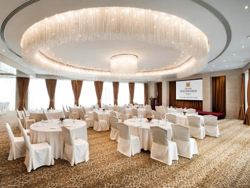 a banquet hall with white tables and chairs and a large chandelier at Grand Millennium Dubai in Dubai