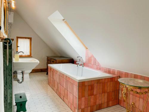 a attic bathroom with a tub and a sink at Cozy Holiday Apartment In The Manor House in Rambin