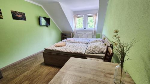 a green bedroom with two beds and a table at Penzion a restaurace Zlatovláska u zámku Červená Lhota in Jižná