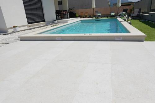 a swimming pool in a yard with a tile floor at PERISKA Home in Kaštela