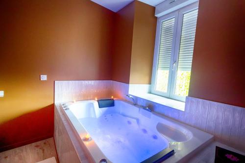 eine große Badewanne im Bad mit Fenster in der Unterkunft Escapade - Ciné privé, balnéo et jardin in Saint-Ambroix