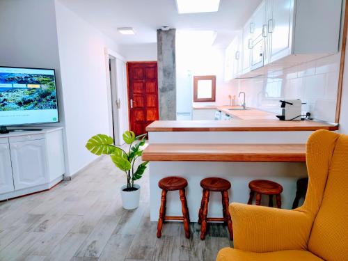 a kitchen with a bar with stools and a tv at VV Duplex Isla Bonita "by henrypole home" in Los Cancajos
