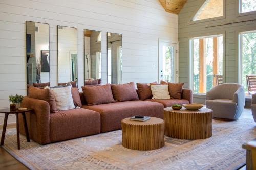 sala de estar con sofá marrón y 2 mesas en Tipi Cabin Lake D'Arbonne, en Farmerville