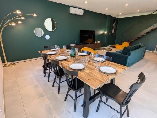 une salle à manger avec une longue table en bois et des chaises dans l'établissement ColorChic 3 étoiles - Parking Privé Terrasse Clim - 120m2 Plein centre, à Mèze